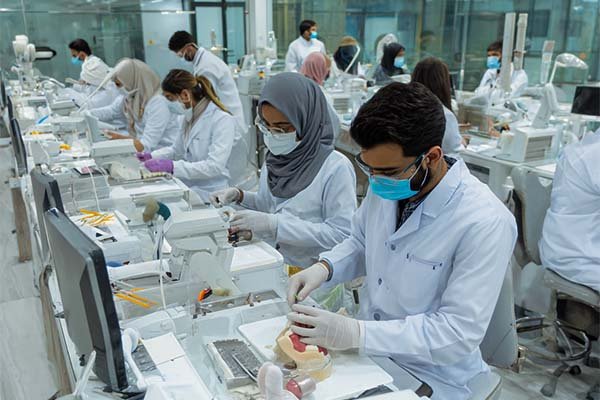Pakistani Dental Technology students in lab coats practicing dental procedures on models in a modern dental lab